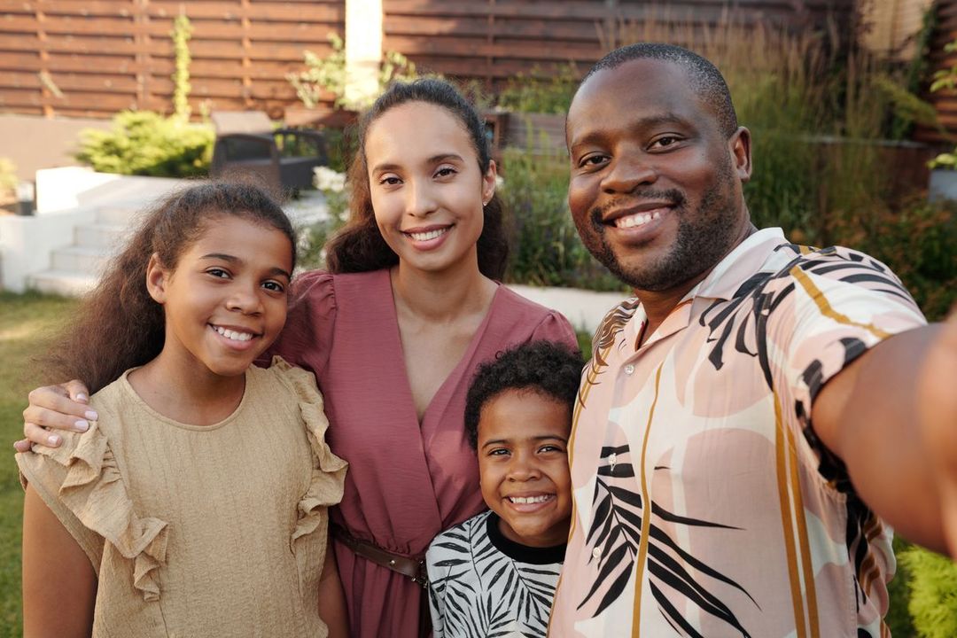 A smiling family taking a photo together outside their home